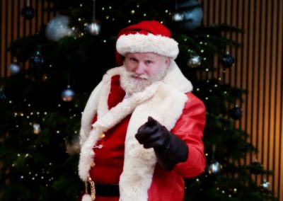 Mighty Fozzy Santa Claus pointing in front of a christmas tree at Newport's Mercure Hotel